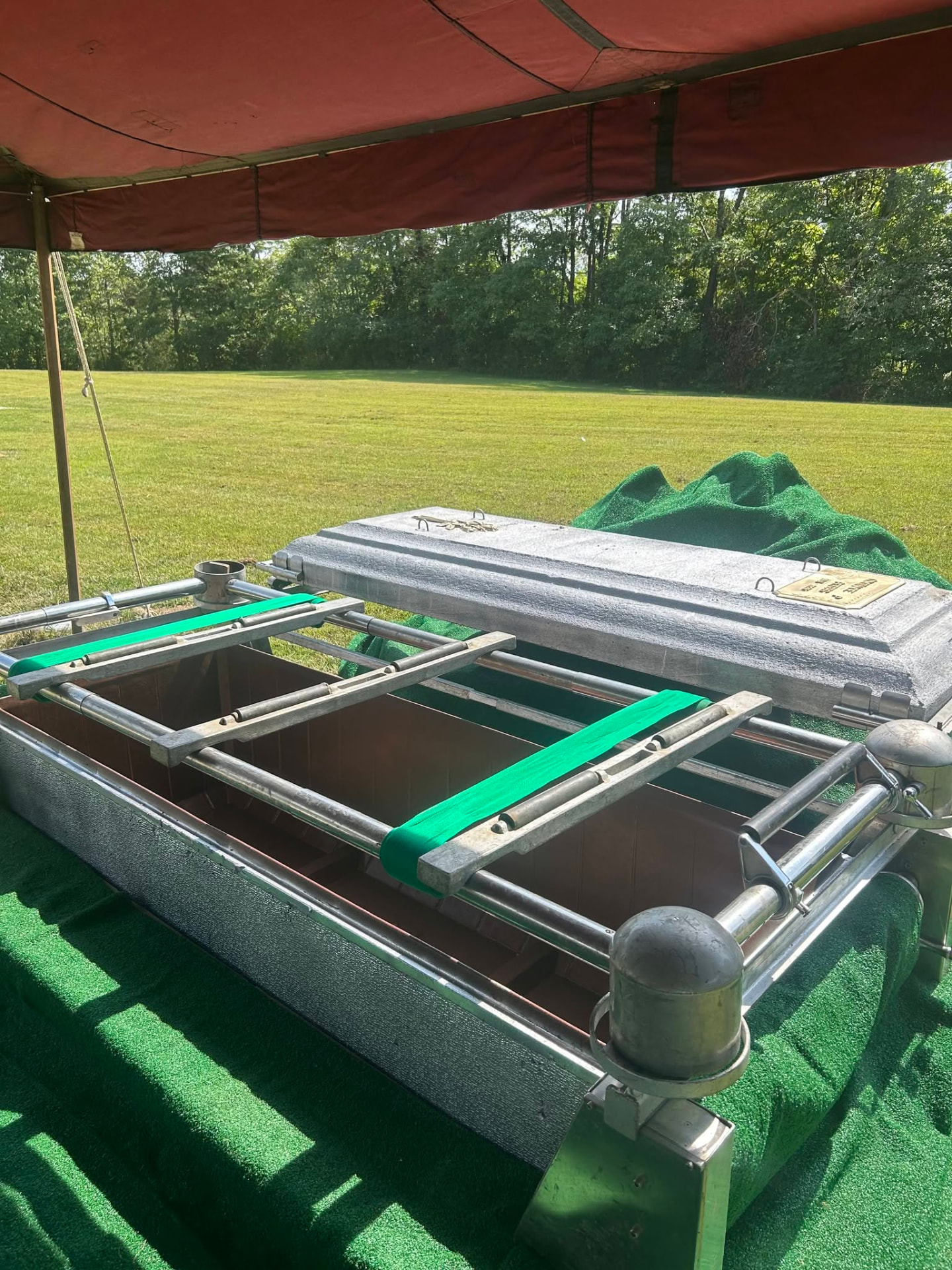 Open burial vault with lowering device and lid ready for a graveside committal