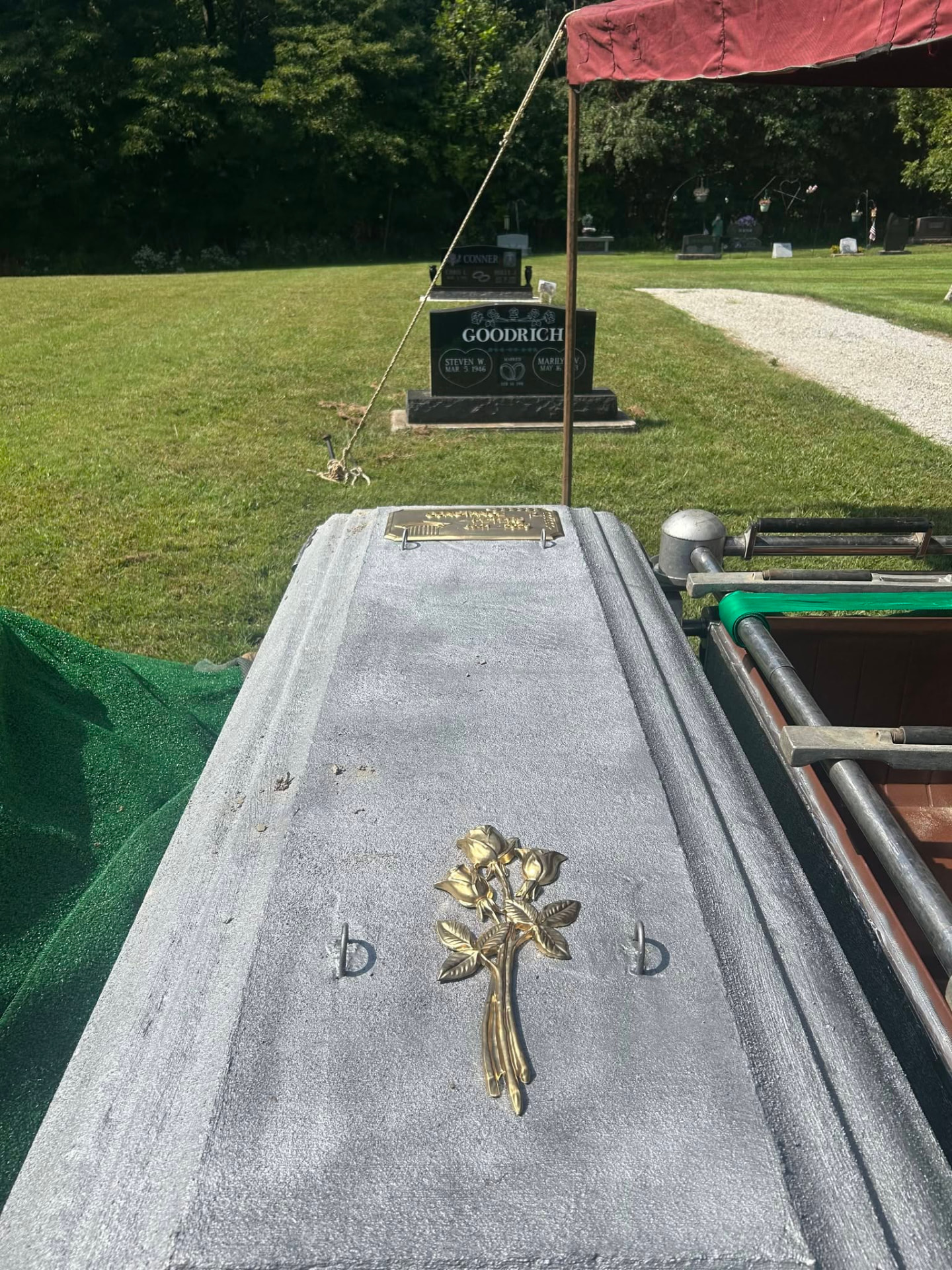 Burial vault lid with gold rose emblem set beside the grave at a Cass County cemetery