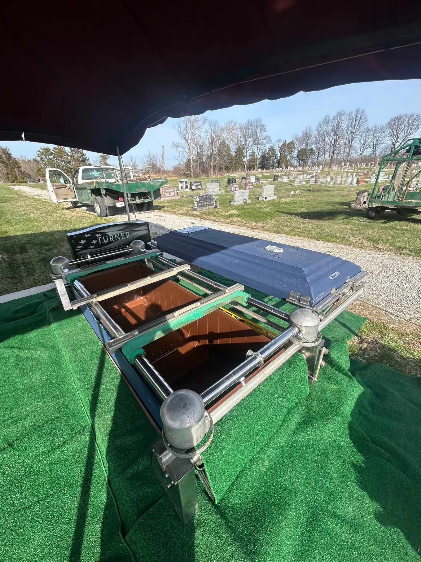 Family Burial Services burial vault open at a graveside service under a funeral tent