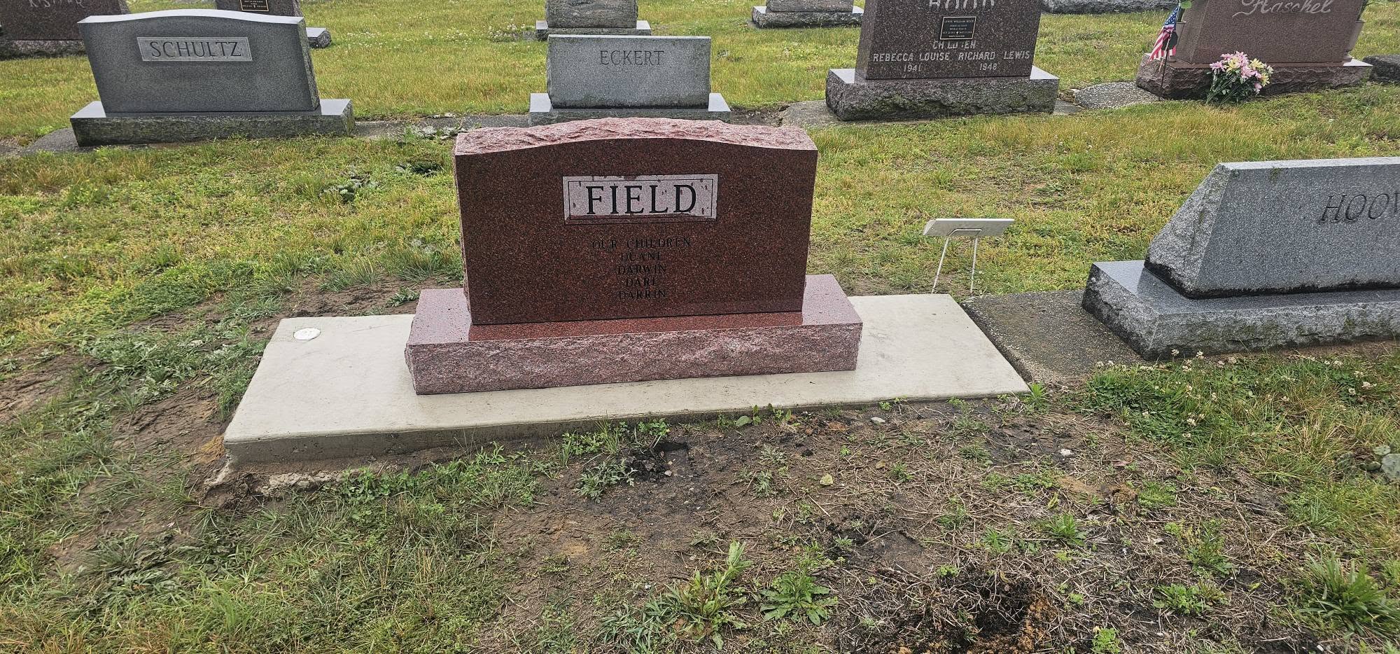 Red granite Field family monument installed on a concrete foundation